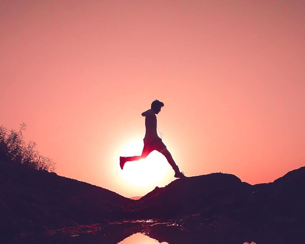 un garçon devant un soleil couchant