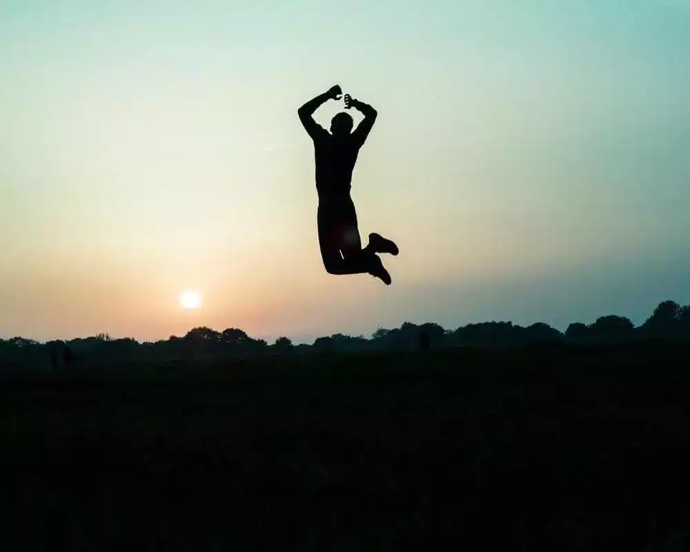 Une personne saute soleil couchant